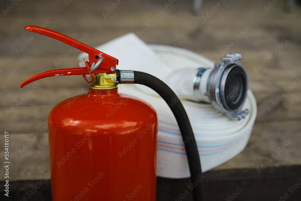 hand presses the trigger fire extinguisher available in fire emergencies conflagration damage background. Safety hand presses the trigger fire extinguisher available in fire emergencies conflagration damage background. Safety