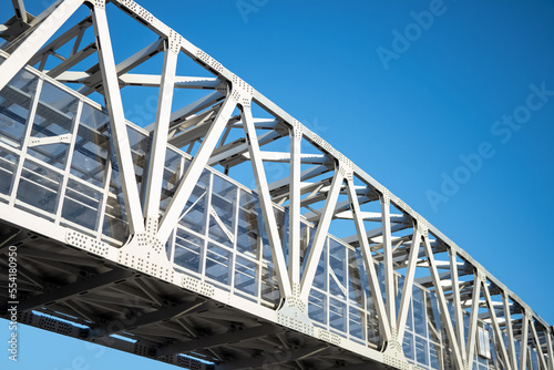 White bridge with bolted metal beams on blue sky background.