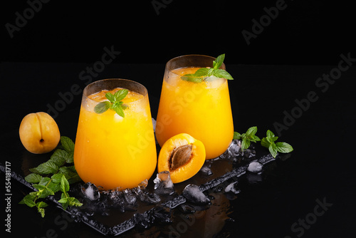 Fresh sweet apricot juice and mint on a black background