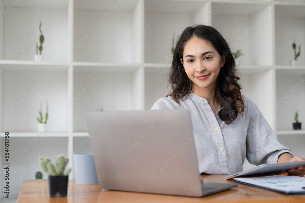 Portrait of an Asian young business Female working on a laptop computer in her workstation.Business people employee freelance online report marketing e-commerce telemarketing concept. Portrait of an Asian young business Female working on a laptop computer in her workstation.Business people employee freelance online report marketing e-commerce telemarketing concept.