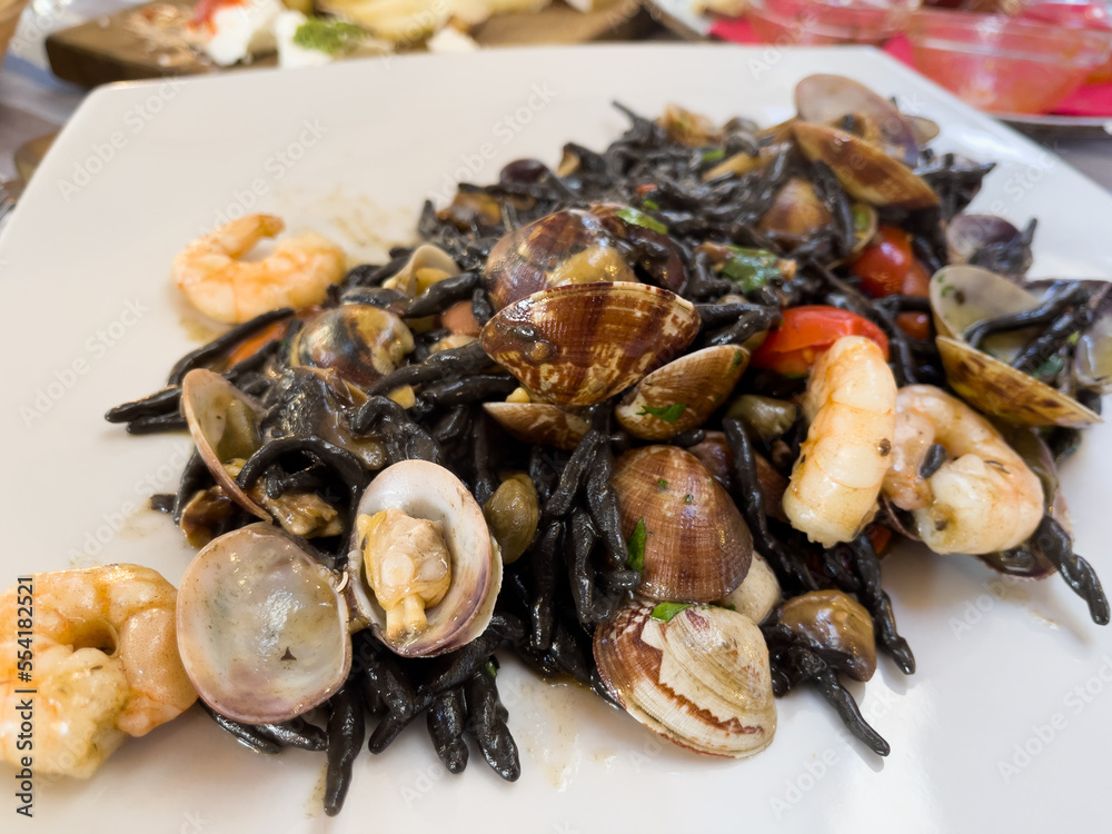 Black pasta with clams and shrimps. Italian seafood on white plate Black pasta with clams and shrimps. Italian seafood on white plate