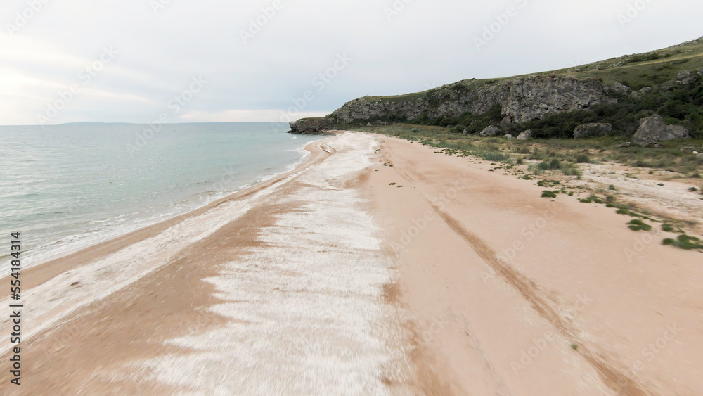 Top view of sandy wild beach with beautiful sea. Shot. Beautiful view of sandy beach with mountains and sea horizon. Empty wild beach with sand