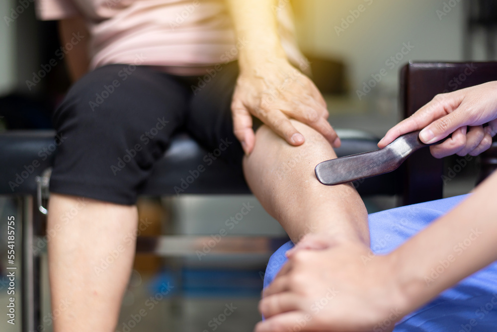 Woman massaging with gua sha wood stick on leg,Reflexology spot thai massage Woman massaging with gua sha wood stick on leg,Reflexology spot thai massage