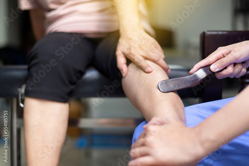 Woman massaging with gua sha wood stick on leg Reflexology spot thai massage