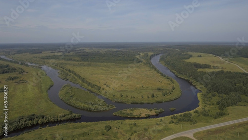 Top view of beautiful river turns on background of green fields. Stock footage. Summer panorama of green fields and river mouths. Beautiful rivers on green fields in summer
