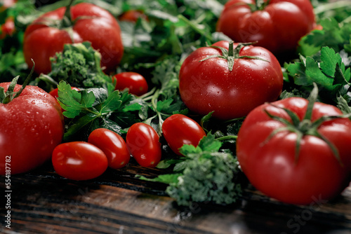 variety of tomatoes and herbs on a wooden table.