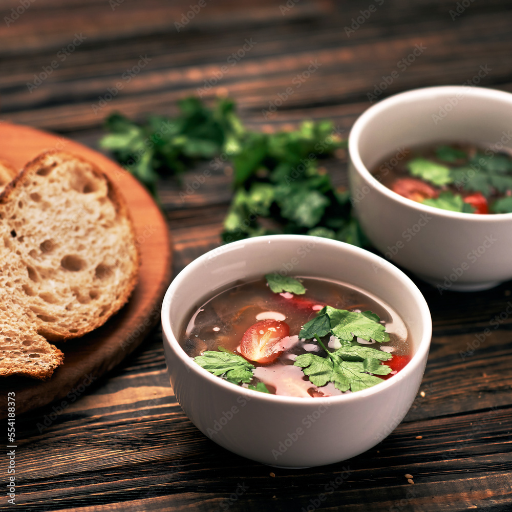 slice of bread and two plates of soup on a wooden board. slice of bread and two plates of soup on a wooden board.