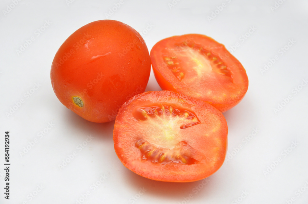 Whole and halved fresh tomatoes on a white background