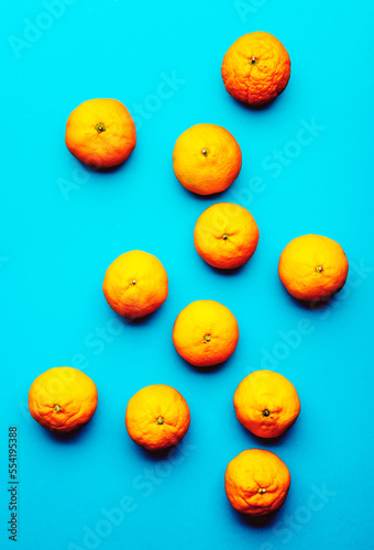 Ripe bright orange tangerines on blue background, fruit pattern. Top view, hard light