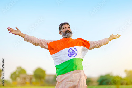 Indian farmer holding indian flag at agriculture field.