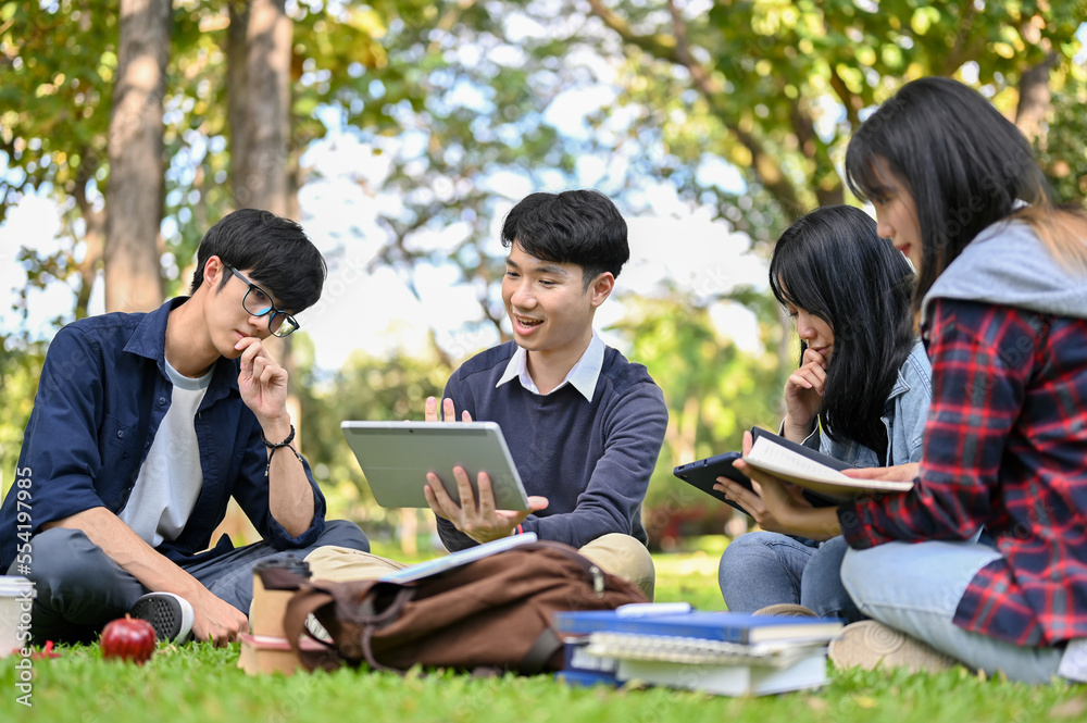 A group of smart young Asian college students doing their project together in the campus's park. A group of smart young Asian college students doing their project together in the campus's park.