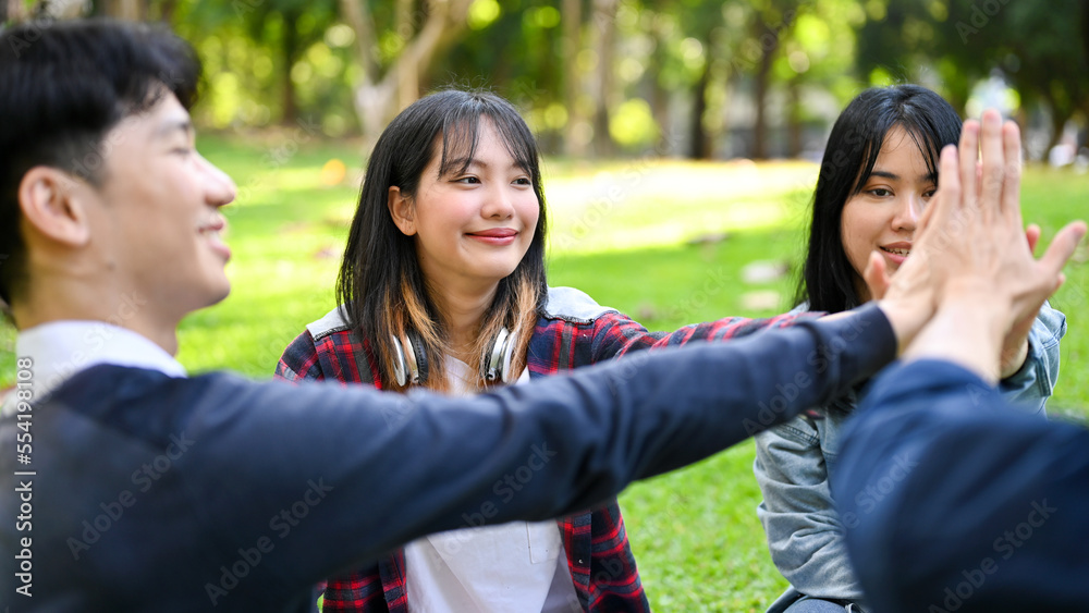 Cheerful Asian friends putting hands together as a teamwork. celebrating, cheering up Cheerful Asian friends putting hands together as a teamwork. celebrating, cheering up