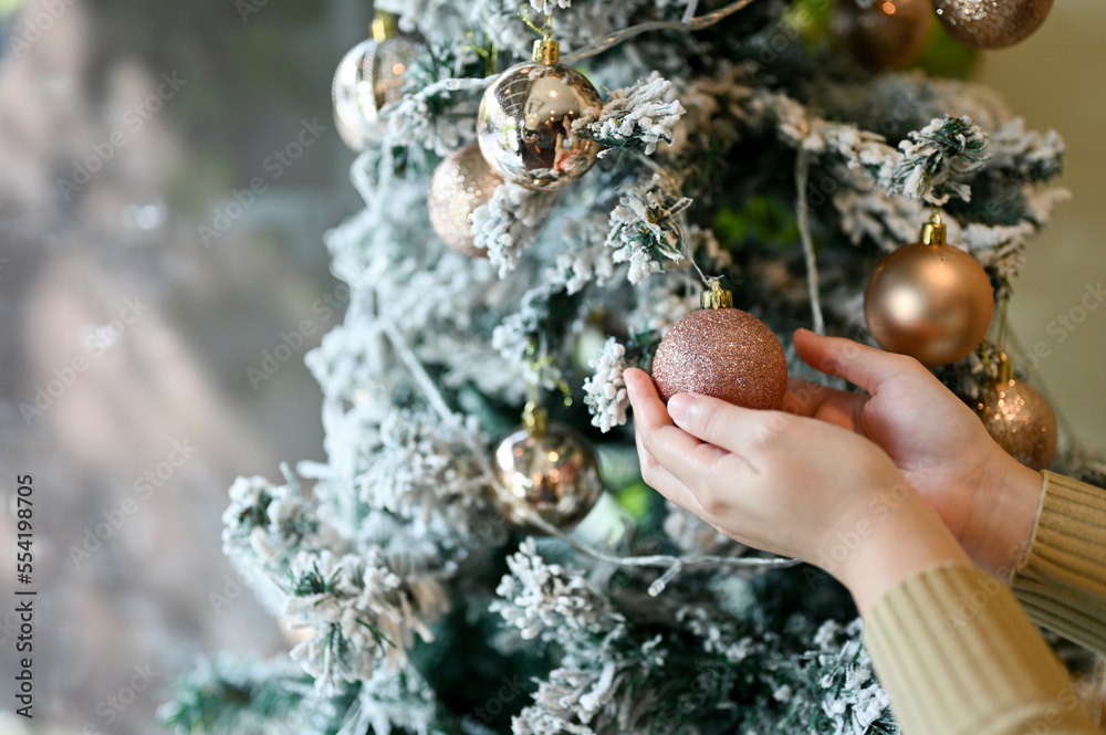 A female decorating her Christmas tree in the living room. close-up image.