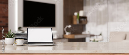 Laptop mockup and copy space on white marble tabletop against blurred background of living room © bongkarn