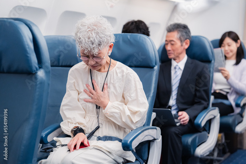 飛行機の機内で体調不良に苦しむ高齢の女性