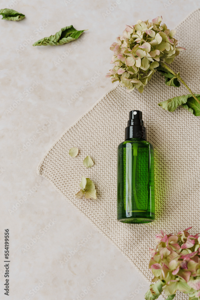 Eine grüne Aroma Sprayflasche und Blumen auf einem beigen Tisch. Draufsicht, Wellness. Eine grüne Aroma Sprayflasche und Blumen auf einem beigen Tisch. Draufsicht, Wellness.