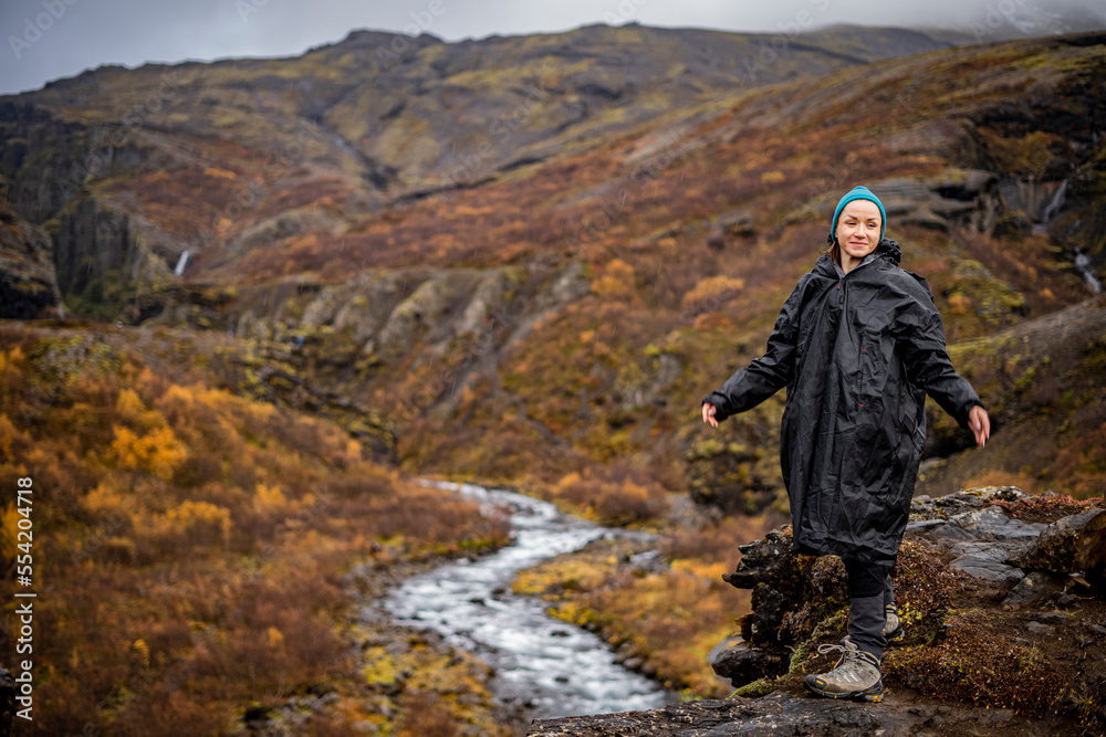 young womanic raincoat on cliff at river in mountains young womanic raincoat on cliff at river in mountains