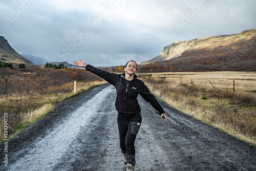 happy young woman walking on road with mountains on background © Sid Smith