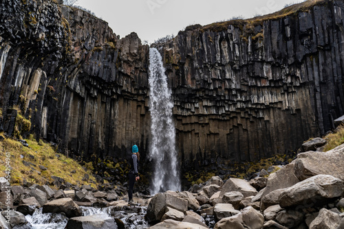 young woman in leggins at Svartifoss waterfall with basaltic columns