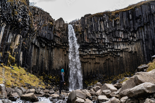 young woman in leggins at Svartifoss waterfall with basaltic columns