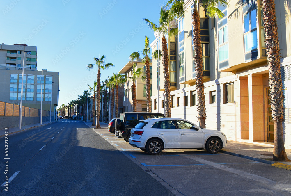 Villa at seaside. Apartment Patacona Beach (Alboraya) Macflats Playa. Houses at beach. Facade building with Palm trees. Penthouse apartments in Spain. Cars at parking lot near empty road on street.