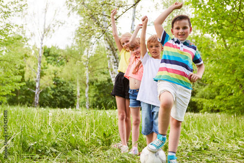 Multiracial friends with hands raised on grass in park