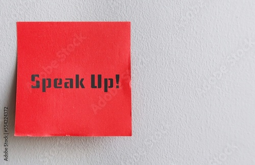 Foto Red note on copy space gray wall with text SPEAK UP ! , self reminder to raise v