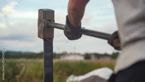Sledgehammer hammering steel stake in ground. Driving a metal pile photo