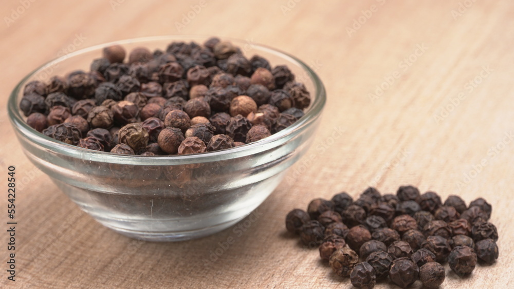 Black pepper in clay bowl on wood background with copy space. Healthy eating, ayurveda, naturopathy concept. Black pepper in clay bowl on wood background with copy space. Healthy eating, ayurveda, naturopathy concept.