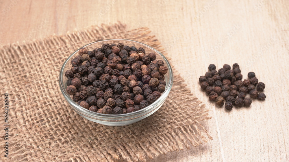 Black pepper in clay bowl on wood background with copy space. Healthy eating, ayurveda, naturopathy concept. Black pepper in clay bowl on wood background with copy space. Healthy eating, ayurveda, naturopathy concept.