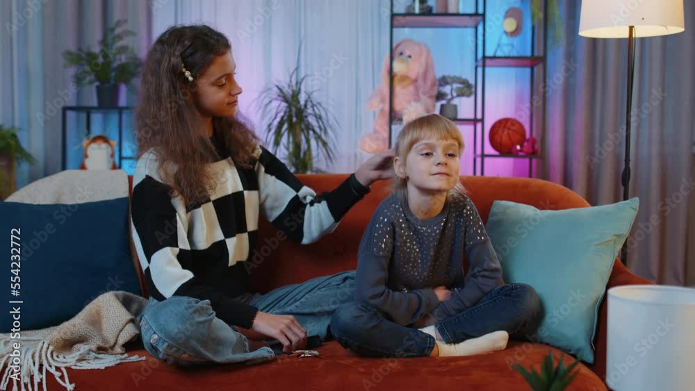 Teenage and little sisters child kids using combs brushing make hairstyle coiffure. Female siblings children or best friends combing long hair at home play room. Family slumber party, plaiting hair Teenage and little sisters child kids using combs brushing make hairstyle coiffure. Female siblings children or best friends combing long hair at home play room. Family slumber party, plaiting hair