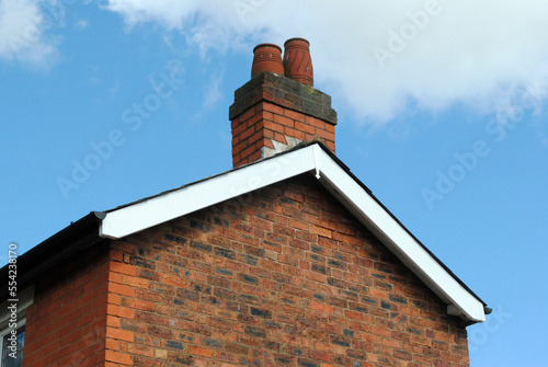 Gable and Chimney Stack of Brick Building seen against Blue Sky