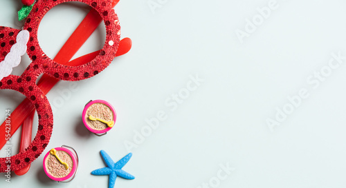 Red glasses and fake starfish for Christmas decoration on green background.