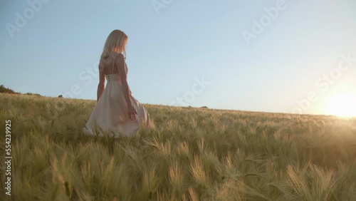 Astonishing nature with lavish harvest below sunset skyline in the background. Low-angle shot of blonde-haired, caucasian woman enjoying natural environment of countryside. High quality 4k footage