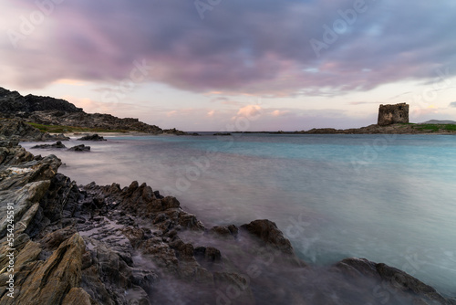 landscape with rocky shore at sunset and the Torrre de la Pelosa watchtower in northern Sardinia