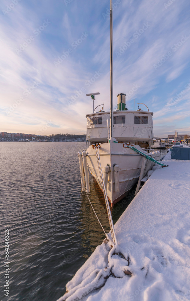 Naklejka premium Moored old steam ship at the pier Norr Mälarstrand a pale snowy winter day in Stockholm