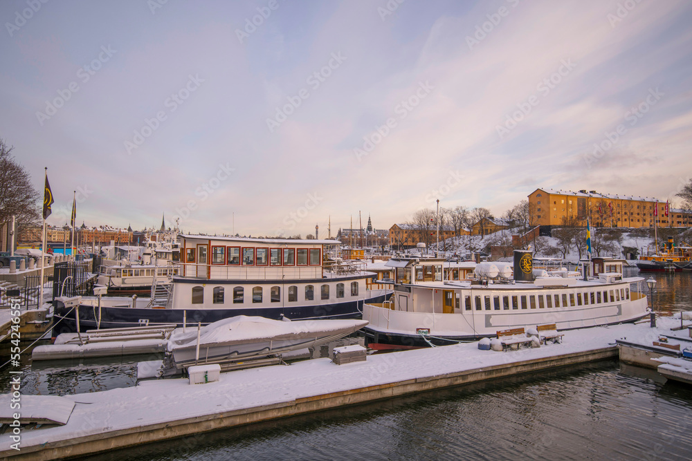 Naklejka premium View from the bridge Skeppsholmsbron moored commuting boat in background a pale snowy winter day in Stockholm