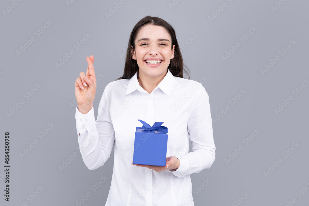 Woman with gift. Funny girl crossed fingers for good luck. Portrait of excited young girl holding gift box, isolated grey background. Pretty girl with present. Woman with gift. Funny girl crossed fingers for good luck. Portrait of excited young girl holding gift box, isolated grey background. Pretty girl with present.
