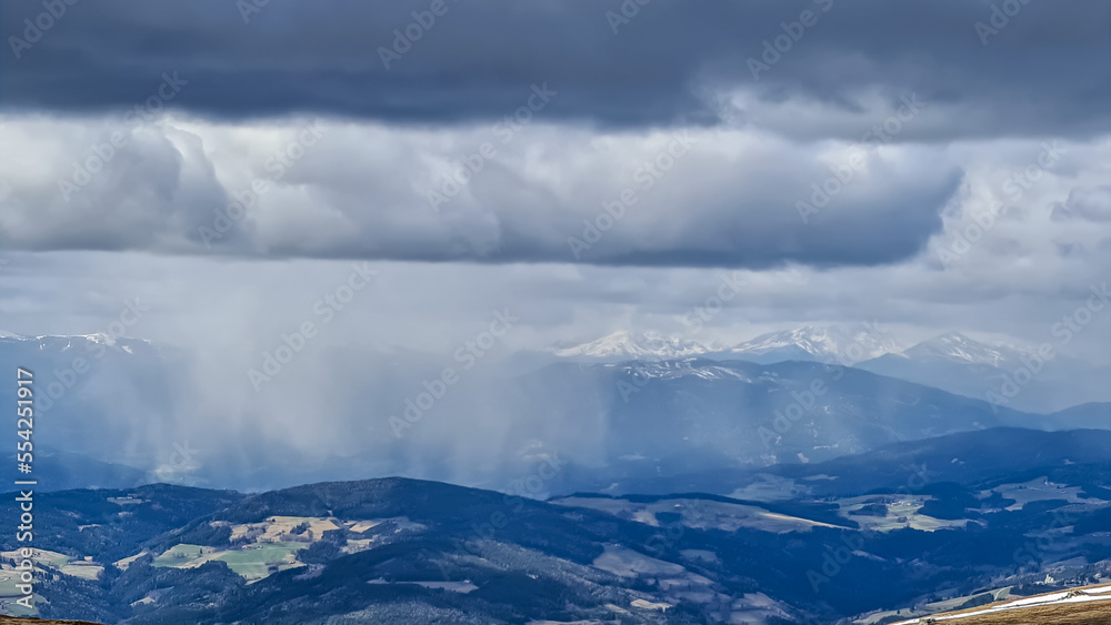 Rainclouds moving across the valley and the mountains of Seckauer Alps seen from Saualpe, Carinthia, Austria, Europe. Dark clouds accumulating and storm emerging. Thunder and rain over Central Alps Rainclouds moving across the valley and the mountains of Seckauer Alps seen from Saualpe, Carinthia, Austria, Europe. Dark clouds accumulating and storm emerging. Thunder and rain over Central Alps