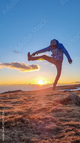 Silhouette of happy man jumping during a beautiful sunset on mountain peak Ladinger Spitz, Saualpe, Lavanttal Alps, Carinthia, Austria, Europe. Warm atmosphere, inspiration, goal seeking concept