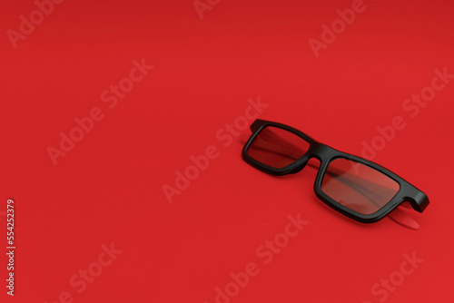 Black sunglasses lying on a red background