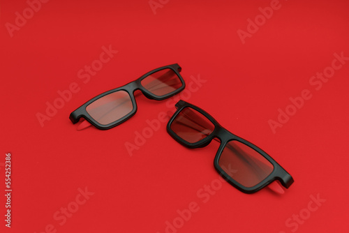 Black sunglasses lying on a red background