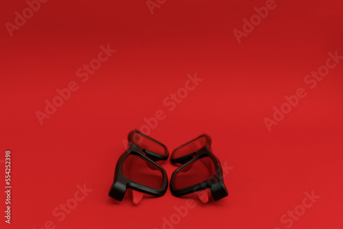 Black sunglasses lying on a red background