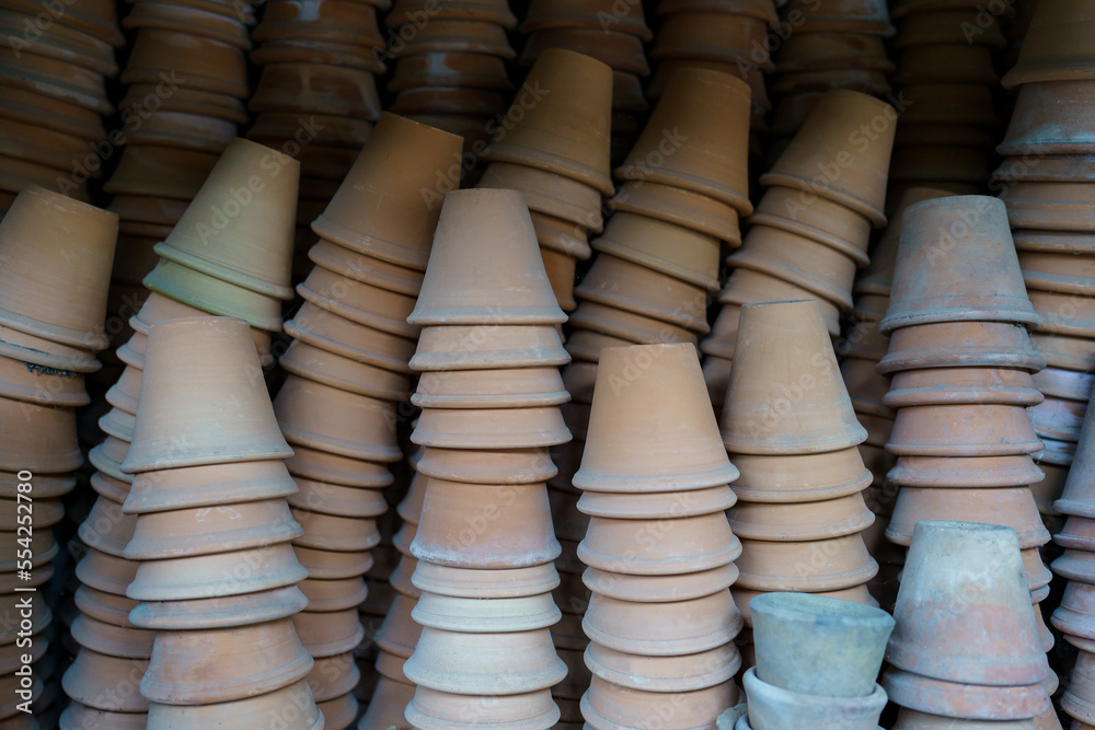 Closeup of stacks of terracotta flower pots in a garden shed. Empty vintage flower pots in greenhouse