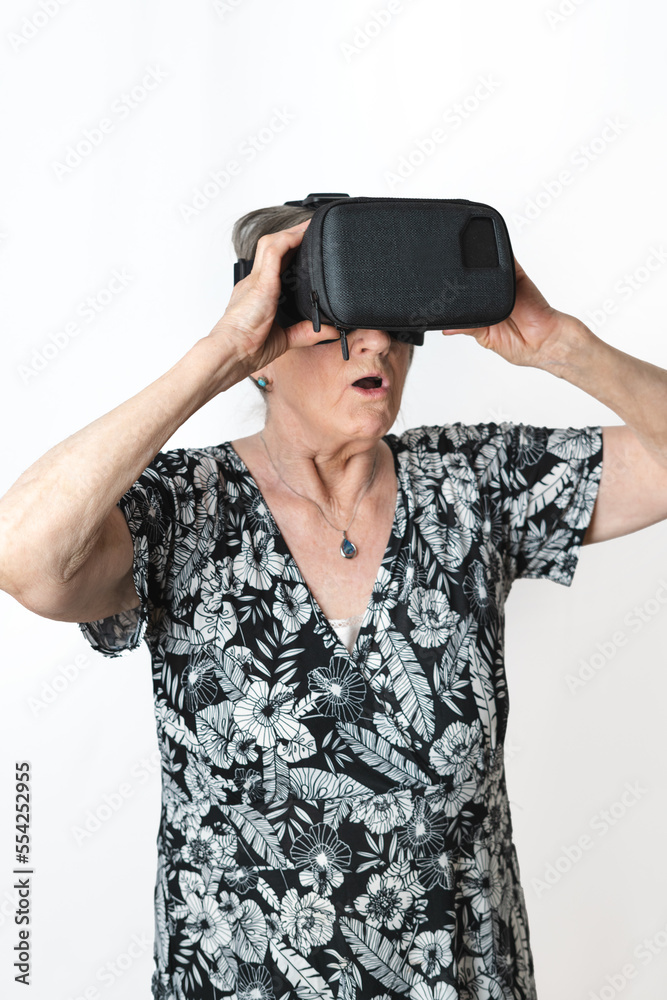 Old retired woman living the experience of Virtual Reality mask. Isolated white background Old retired woman living the experience of Virtual Reality mask. Isolated white background