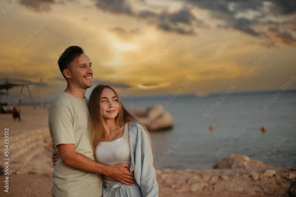 couple in love on the shore of the beach of the sea walks on a date. Young family couple in summer clothes on a honeymoon trip. couple in love on the shore of the beach of the sea walks on a date. Young family couple in summer clothes on a honeymoon trip.