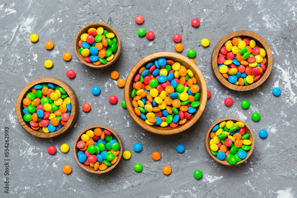 different colored round candy in bowl and jars. Top view of large variety sweets and candies with copy space different colored round candy in bowl and jars. Top view of large variety sweets and candies with copy space