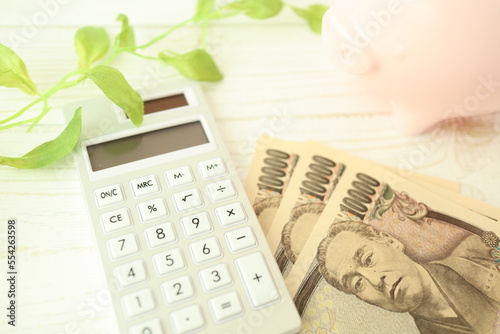 電卓とお金と貯金箱（家計の節約イメージ）