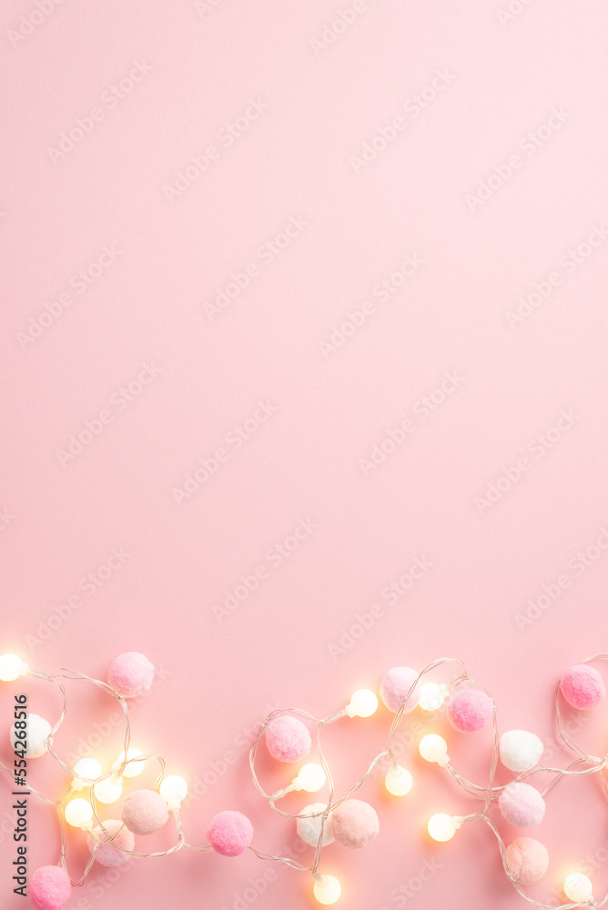 Saint Valentine's Day concept. Top view vertical photo of light bulb garland and fluffy pompons on isolated pastel pink background with empty space