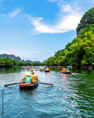 Fototapeta Naklejka Na Ścianę i Meble -  Tourists sitting on rowing boats enjoy the beautiful scenery of rivers and mountains in Trang An, Ninh Binh province, Vietnam.